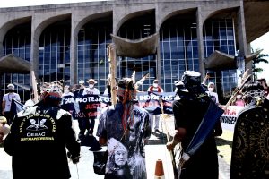 Círculo dos manifestantes em frente ao Ministério da Justiça. Alguns levam flechas, outros carregam uma faixa exigindo direitos para os indígenas e justiça para Dom e Bruno.