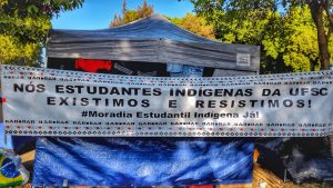 Faixa à frente da maior tenda do acampamento: Nós, estudantes indígenas da UFSC, existimos e resistimos! #Moradia Estudantil Indígena Já!