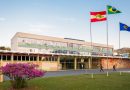 Frente do prédio da Reitoria da UFSC. As paredes têm azulejos coloridos e na frente há as bandeiras do Brasil, de Santa Catarina e da UFSC.